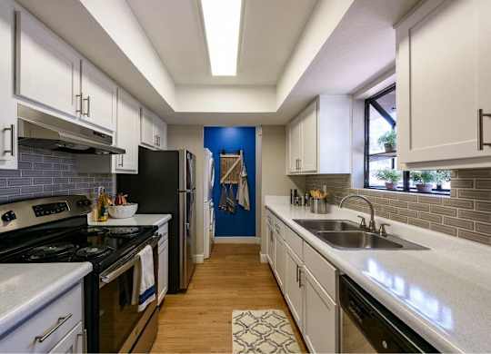 A kitchen with white cabinets and a black refrigerator.