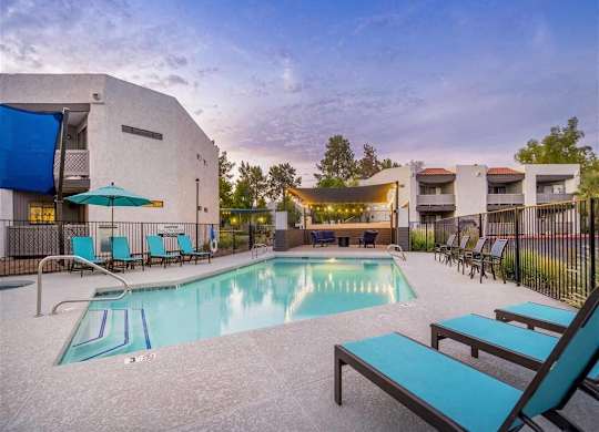 A swimming pool with lounge chairs and a building in the background.