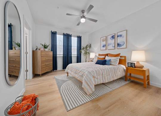 A bedroom with a bed, a dresser, a mirror, and a ceiling fan.