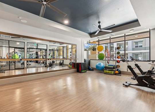 A gym with a variety of exercise equipment and a large mirrored wall.