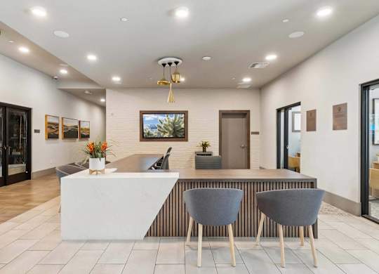 A reception area with a white counter and two grey chairs.