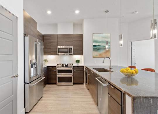A modern kitchen with a refrigerator, oven, and sink.