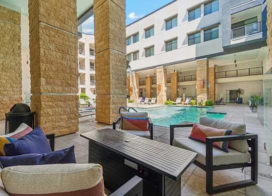 A modern outdoor seating area with a pool in the background.