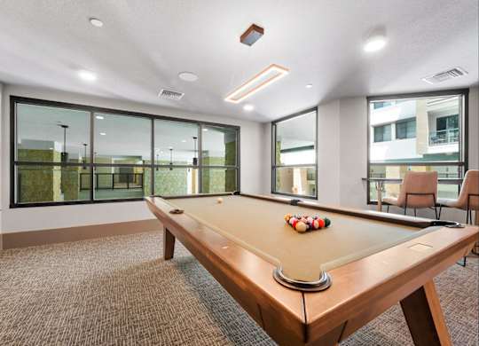 A pool table in a room with a brown carpet.