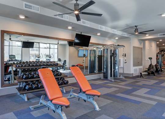 A gym with orange chairs and a mirrored wall.