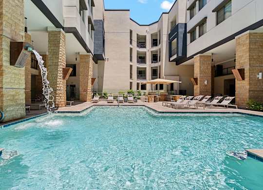 A large swimming pool with a waterfall feature in the middle.