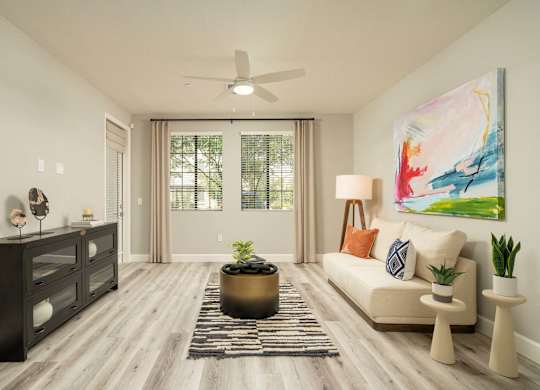 A living room with a beige sofa, a black dresser, and a painting on the wall.