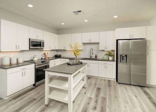 A modern kitchen with white cabinets and a wooden island.