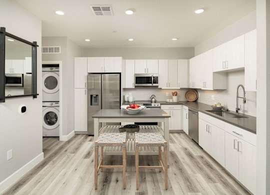 A modern kitchen with a dining table and chairs in the middle.