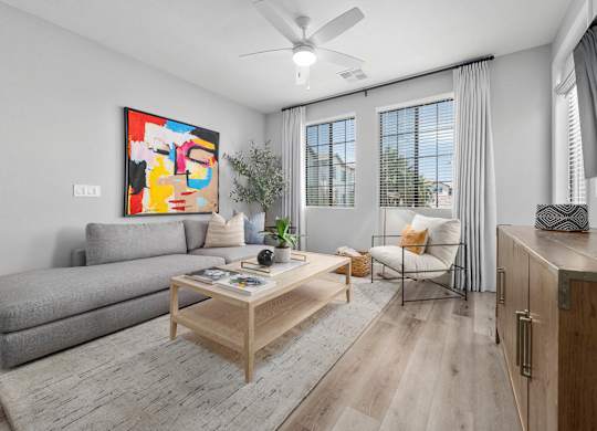 A living room with a grey sofa, a wooden coffee table, and a painting on the wall.