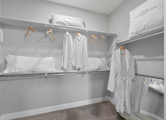 A white hotel room with two beds and towels hanging up.