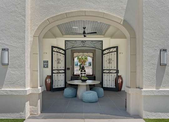 A white building with a black gate and a fan in the middle.