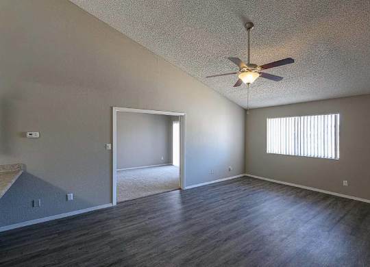 A room with a ceiling fan and a window with blinds.