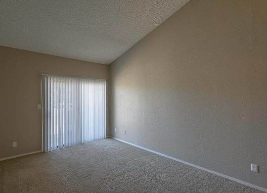 A room with a carpeted floor and a window with blinds.