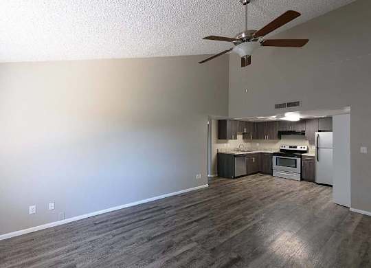 A room with a ceiling fan and a kitchenette.