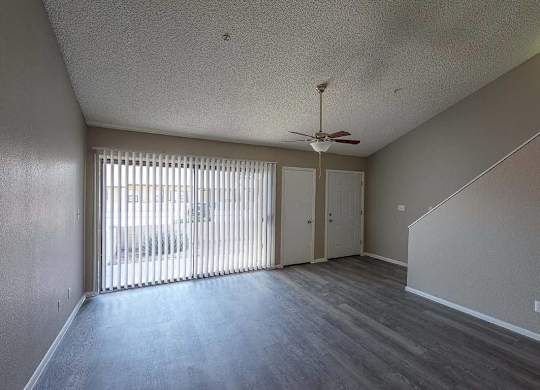 A room with a ceiling fan and sliding glass doors.