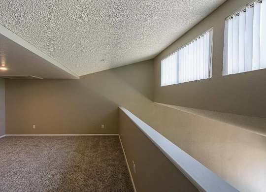A room with a carpeted floor and a window with blinds.