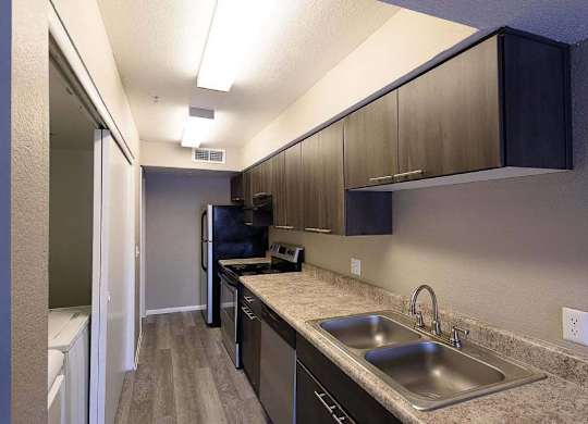 A kitchen with a sink, refrigerator, and cabinets.