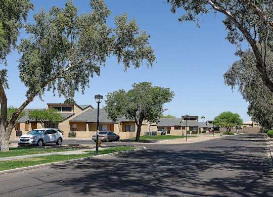 A street view of a residential area with houses and trees.