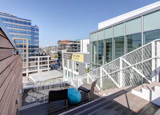 A balcony with a white railing and a blue bean bag chair.
