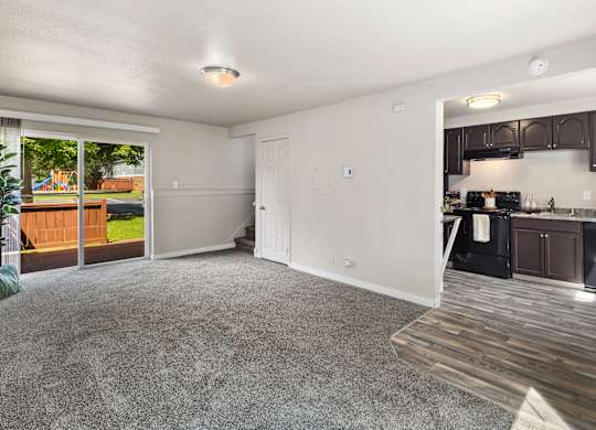 A spacious living room with a kitchen area in the background.