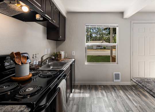 A kitchen with a black stove top oven and wooden handles.