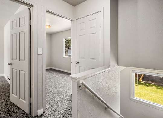 A white door is open to a room with a carpeted floor.