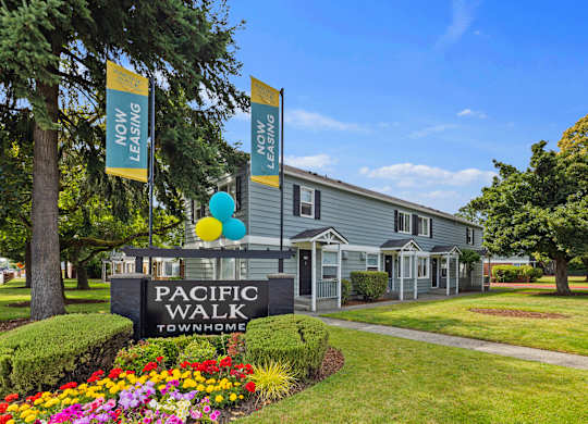 A sign for Pacific Walk Townhome is in front of a building with balloons.