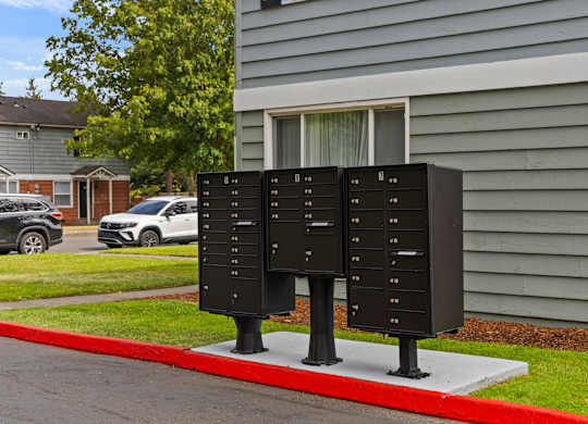 Two black mailboxes stand on a red curb in front of a house.