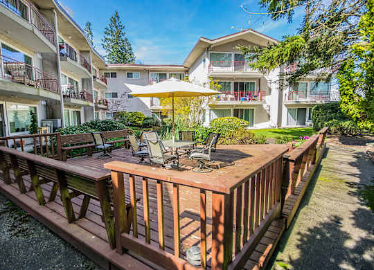 a wooden deck with a table and chairs and an umbrella