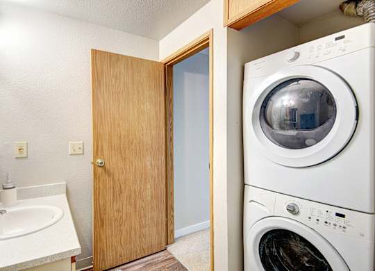 A white washing machine sits in a laundry room next to a sink.