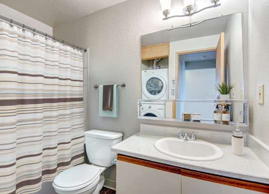 A bathroom with a toilet, sink, and mirror.