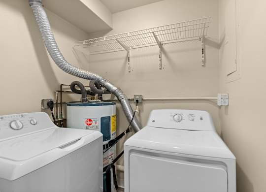 two washers and a dryer in a laundry room with a rack on top