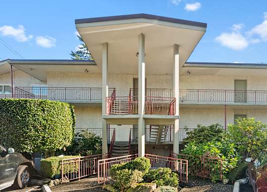 a building with a balcony and a car parked in front of it