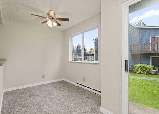 A room with a ceiling fan and a window overlooking a blue house. at Brookstone, Washington, 98198