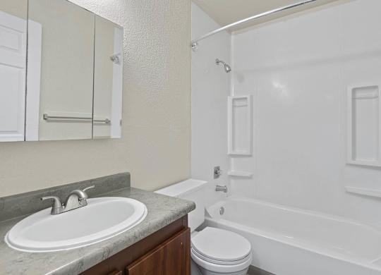 A white bathroom with a sink, toilet, and bathtub. at Brookstone, SeaTac, Washington
