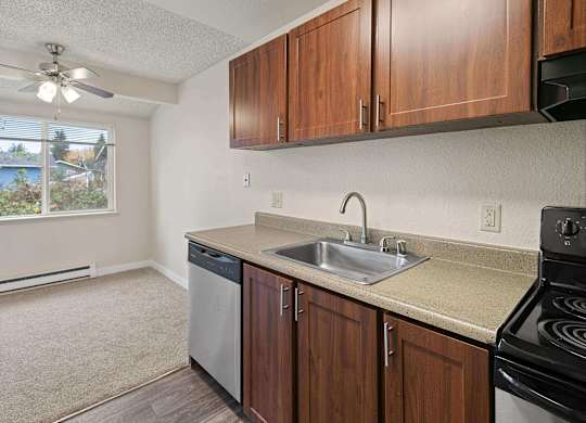 A kitchen with brown cabinets and a black stove top oven. at Brookstone, SeaTac, WA