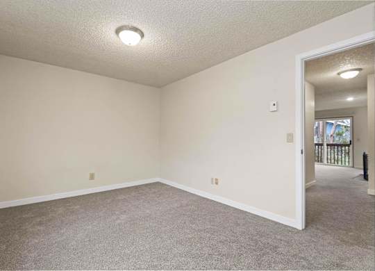 A room with a carpeted floor and a doorway leading to another room. at Brookstone, SeaTac