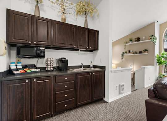 A kitchen with dark wood cabinets and a black microwave.