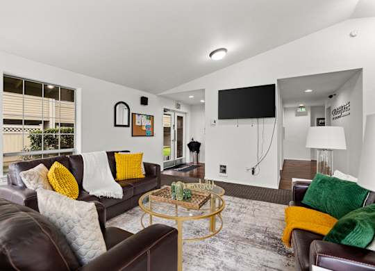 A living room with a brown leather couch and a glass coffee table.