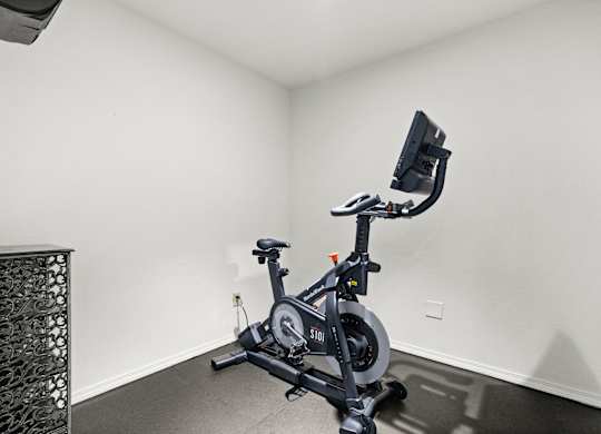 A stationary exercise bike is in a white room.