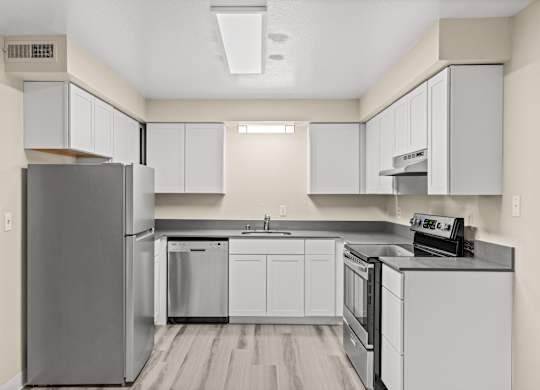 A modern kitchen with white cabinets and stainless steel appliances.