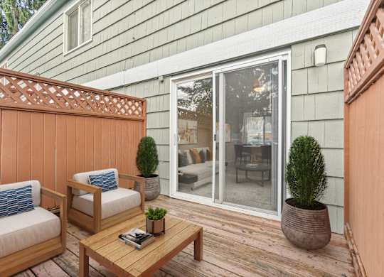 A wooden deck with a table and chairs and a potted plant.