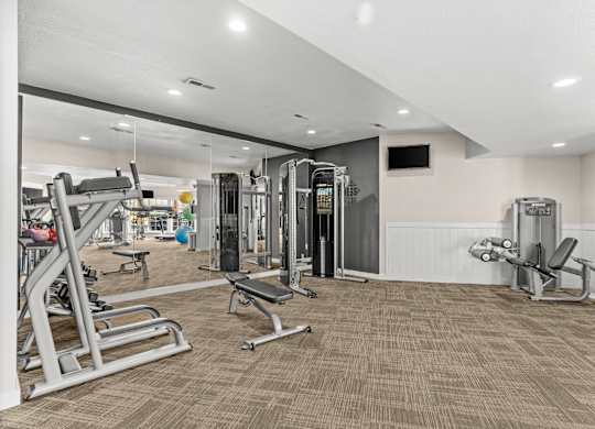 A spacious gym with a variety of equipment including treadmills, weight machines, and benches.