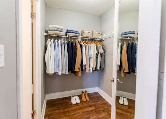 A white closet with clothes and shoes.