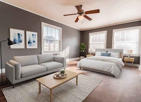 A bedroom with a large bed, a couch, a coffee table, and a ceiling fan.