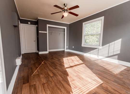 A room with a ceiling fan and wooden flooring.