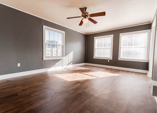 A room with a ceiling fan and wooden flooring.