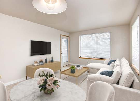 A living room with a white couch, a coffee table, and a flat-screen TV.