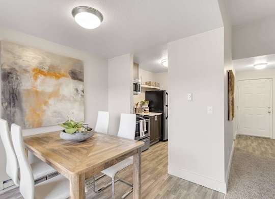 A modern kitchen with a wooden table and white chairs. at Northpoint Apartments, Tacoma